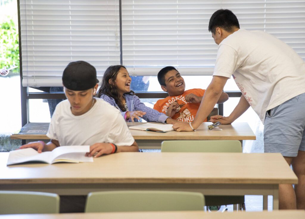 Aranzasu Hernandez Santos, 10 (left), and Kevin Ramirez, 9, laugh with tutor Travis Lee. (Olivia Vanni / The Herald)
