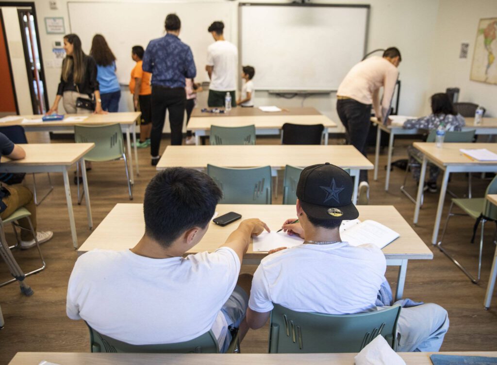 Travis Lee (left) helps a student through a math worksheet. (Olivia Vanni / The Herald)
