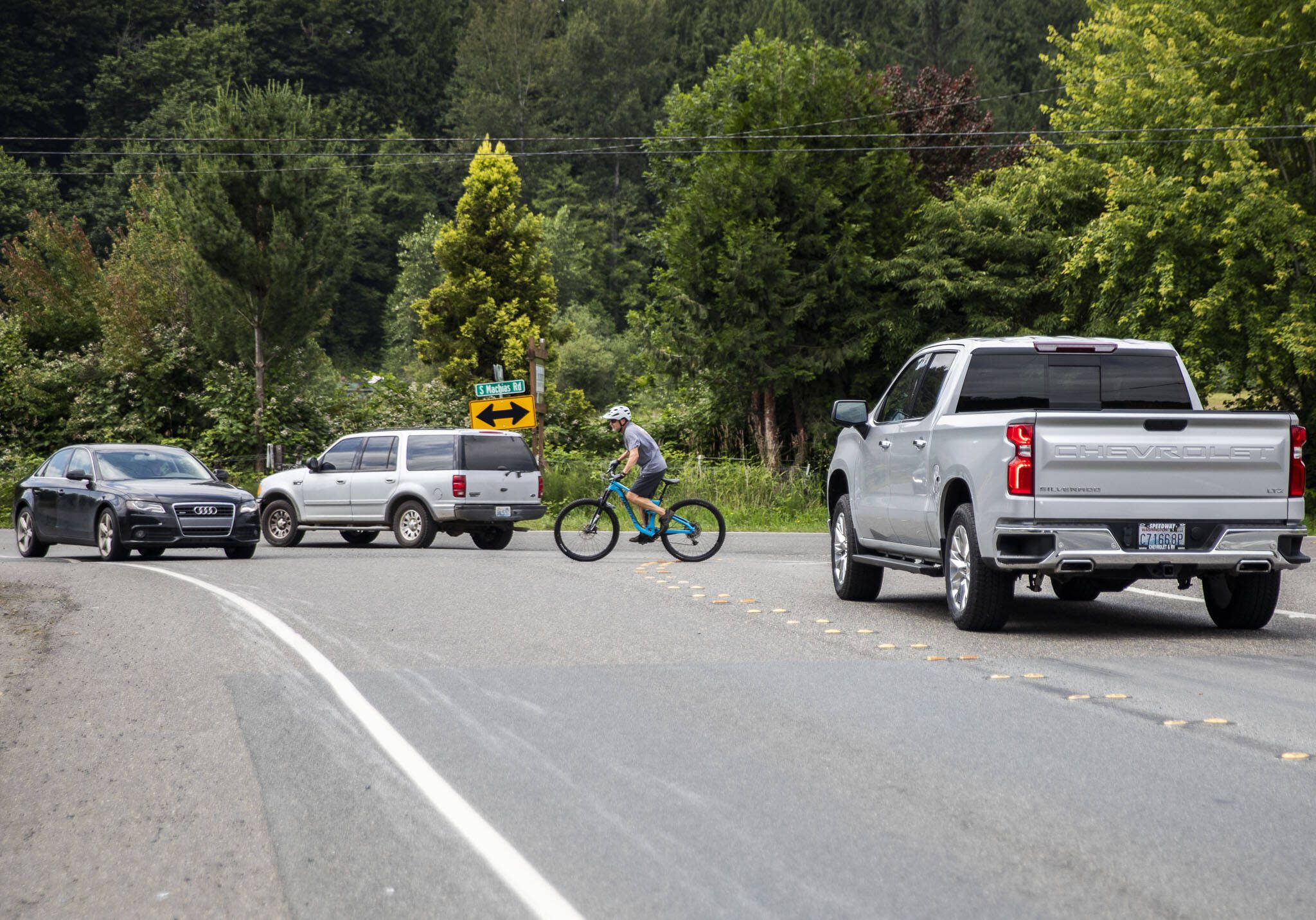 A cyclist, coming from the Centennial Trail, tries to navigate through traffic backed up on Dubuque Road turning onto Machias Road on Tuesday, June 27, 2023 in Snohomish, Washington. (Olivia Vanni / The Herald)
