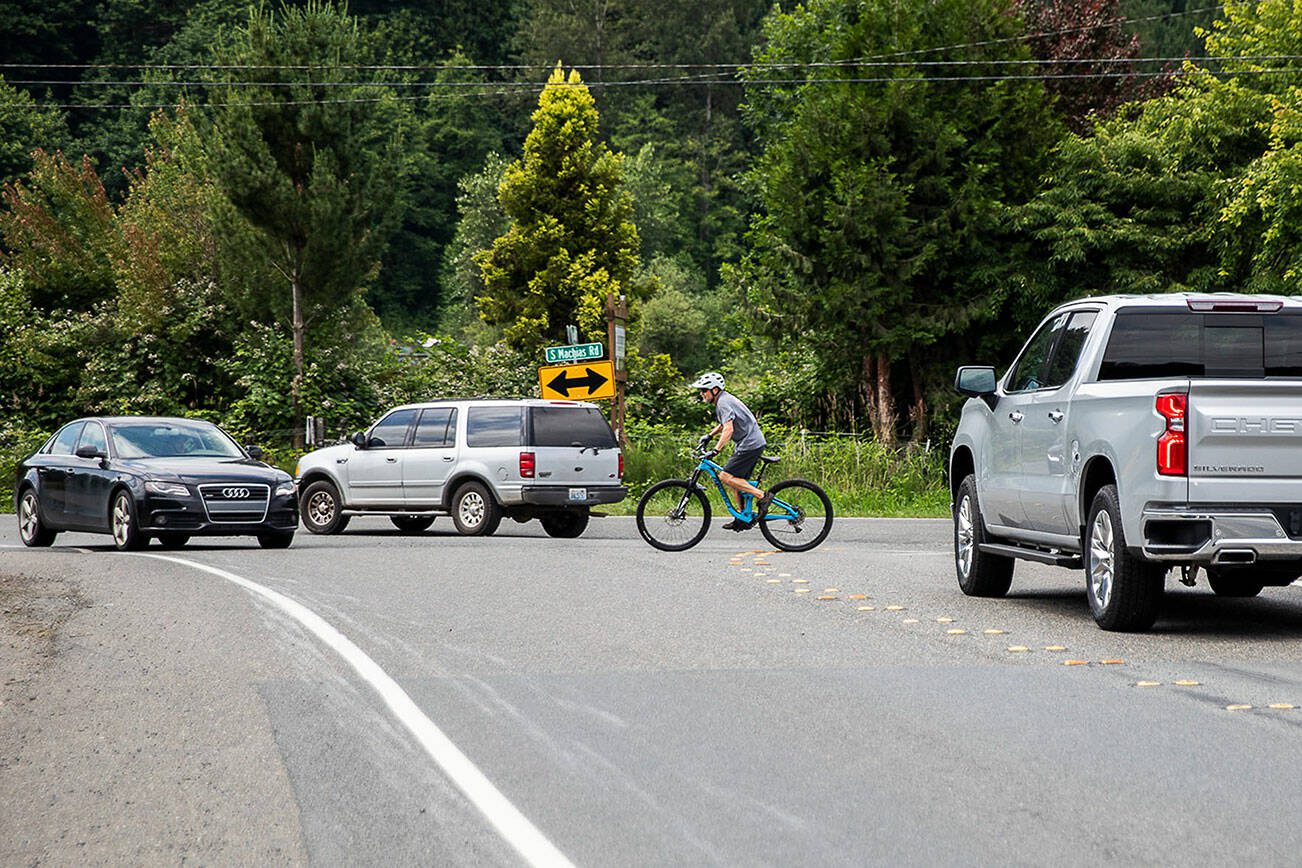 A cyclist from the Centennial Trail tries to navigate through traffic backed up on Dubuque Road turning onto Machias Road on Tuesday, June 27, 2023 in Snohomish, Washington. (Olivia Vanni / The Herald)