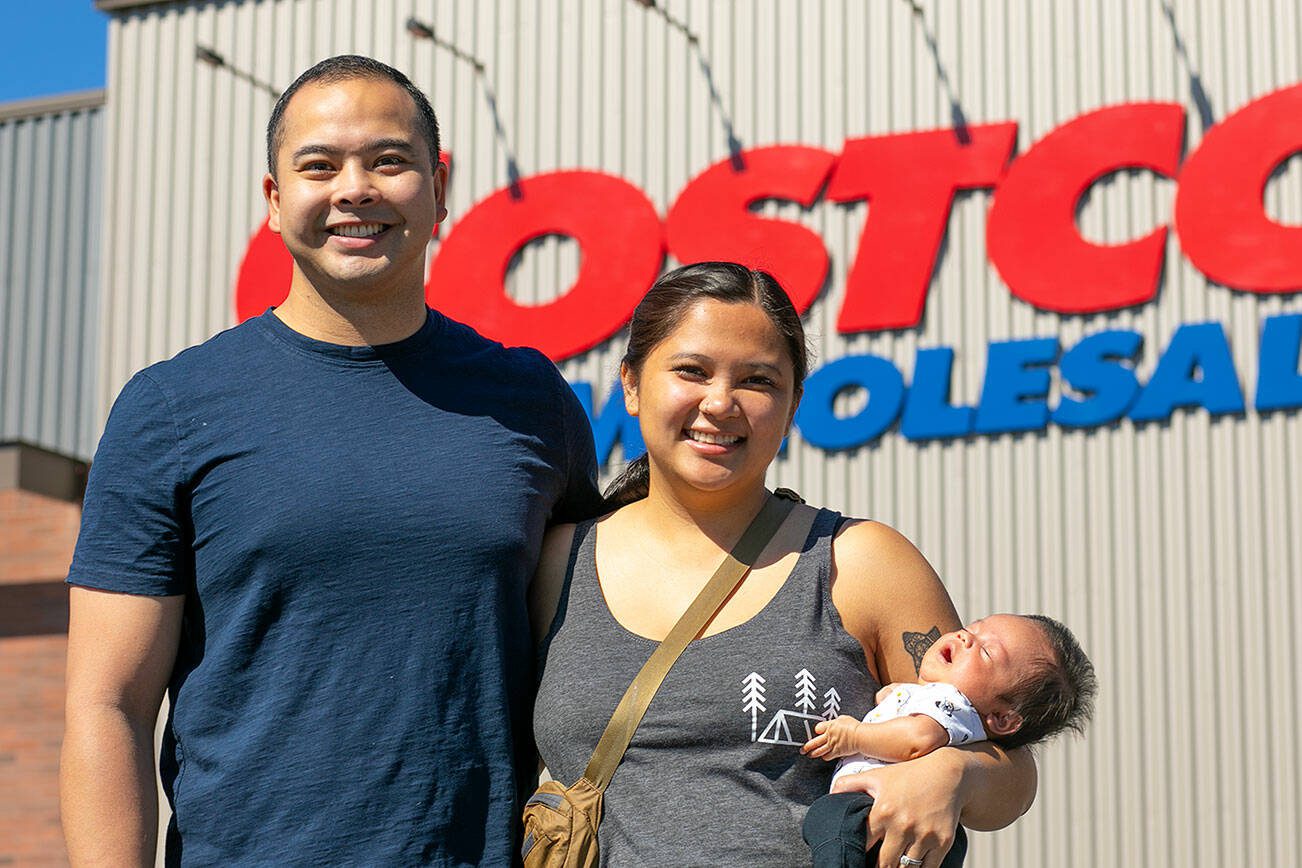 Angelo and Jona Sarmiento, along with 7-week-old Carlisle, stand in front of the Costco where Jona went into labor with the couple's first child in late May on Friday, July 14, 2023, in Lake Stevens, Washington. (Ryan Berry / The Herald)