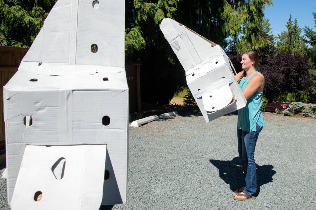 Averio Health Institute CEO Anna Martin, right, puts on a cardboard vertebrae. (Ryan Berry / The Herald)
