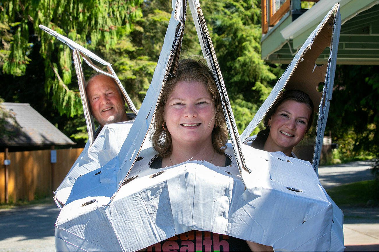 From left: Avery Martin D.C., Sarah Kotlerman D.C. and CEO Anna Martin, all of Averio Health Institute, wear giant cardboard vertebrae made out of banana boxes while demonstrating how they plan to claim the Guinness World Record for largest cardboard costume on Saturday, July 15, 2023, in Mount Vernon, Washington. (Ryan Berry / The Herald)