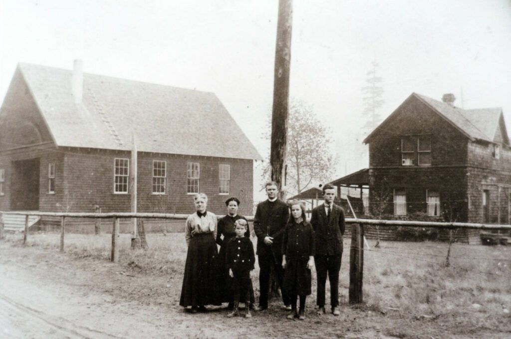 From left, Sarah Ellen Grubb, Delta Pearl Grubb Delong, James Leslie Delong, Frank L. Delong, Ester Delong and Jesse L. Delong in front of the Little Brown Church and the original house on the property in 1916.
