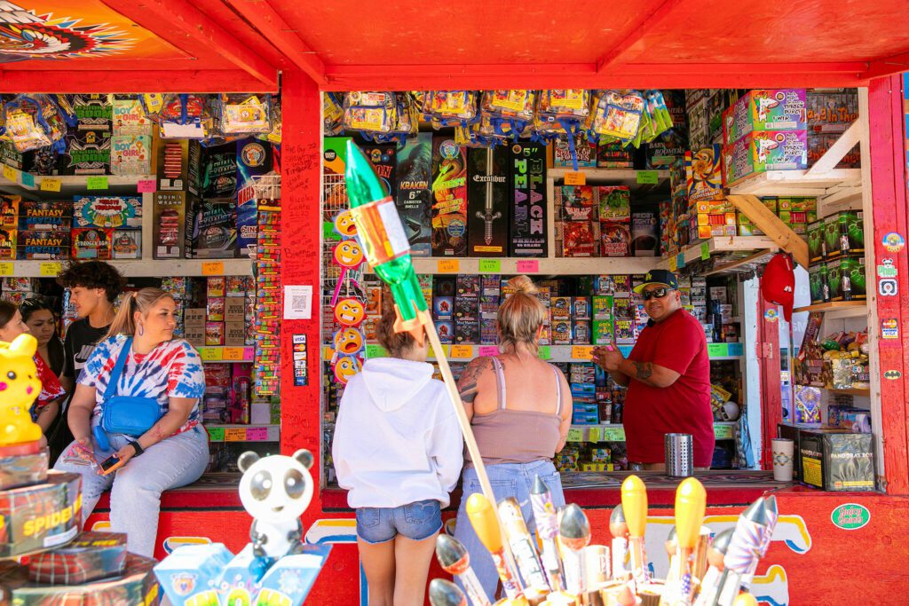 Christopher Joseph, right, who owns Showtime Fireworks with his wife Samora Joseph, chats with a few customers at Boom City on July 1, 2023, in Tulalip, Washington. (Ryan Berry / The Herald)
