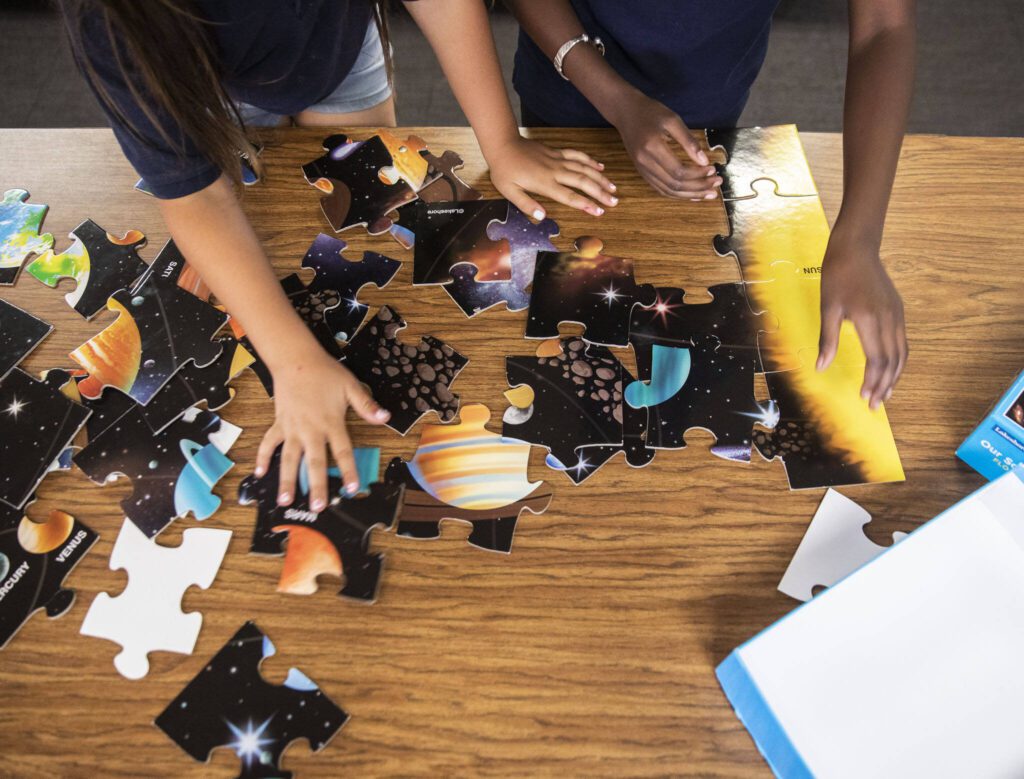 Rise Up Academy students work on putting together a solar system puzzle on Thursday, July 6, 2023 in Everett, Washington. (Olivia Vanni / The Herald)
