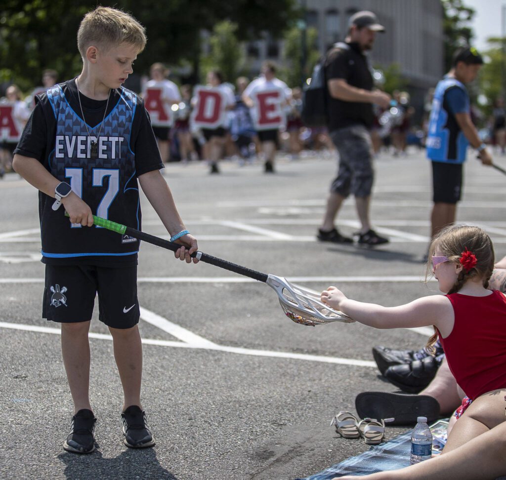 Everett lacrosse players hand out candy during the Everett 4th of July parade in downtown Everett, Washington on Tuesday, July 4, 2023. (Annie Barker / The Herald)
