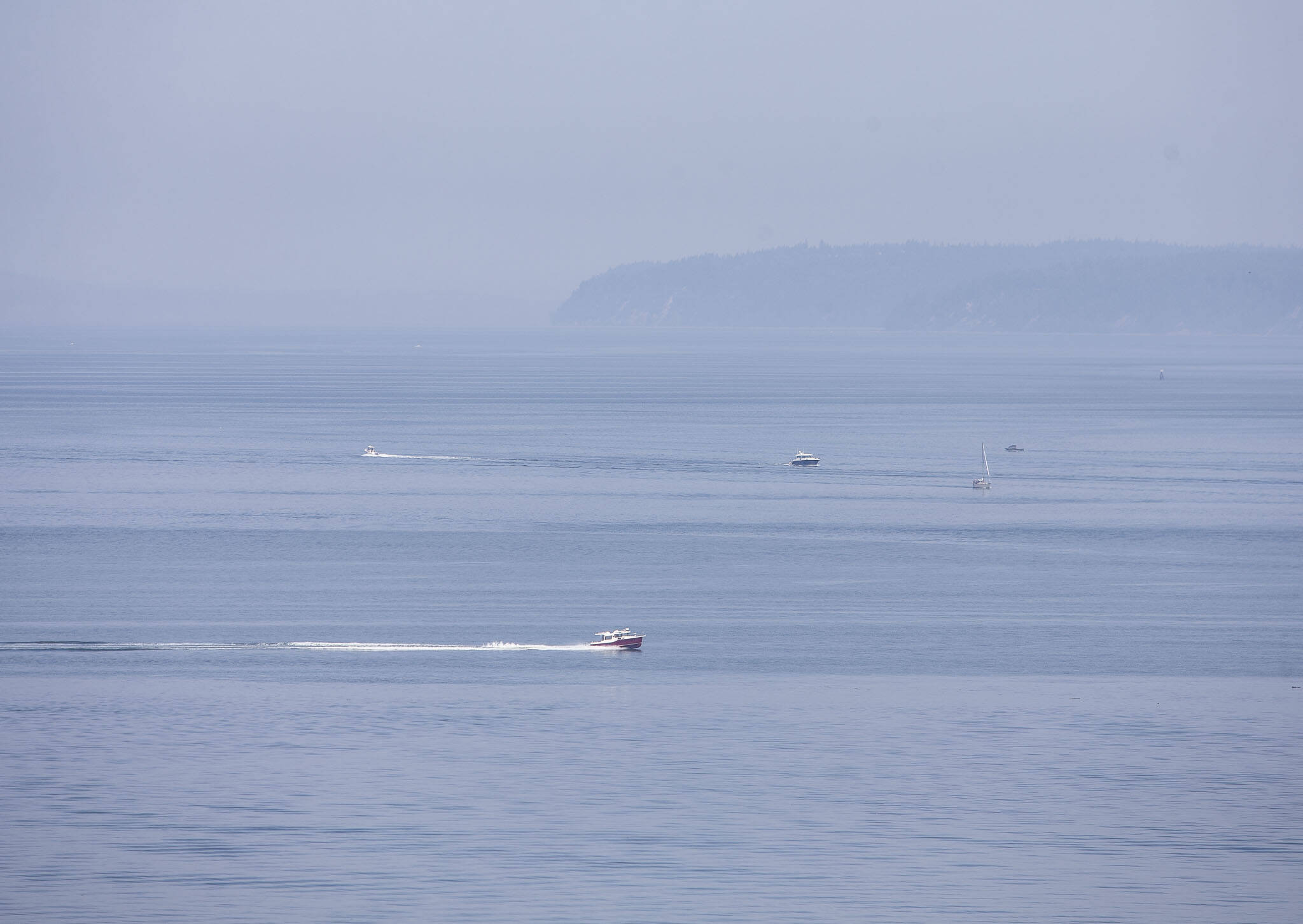 Boats navigate their way across Possession Sound through a visible haze on Wednesday, July 5, 2023 in Everett, Washington. (Olivia Vanni / The Herald)