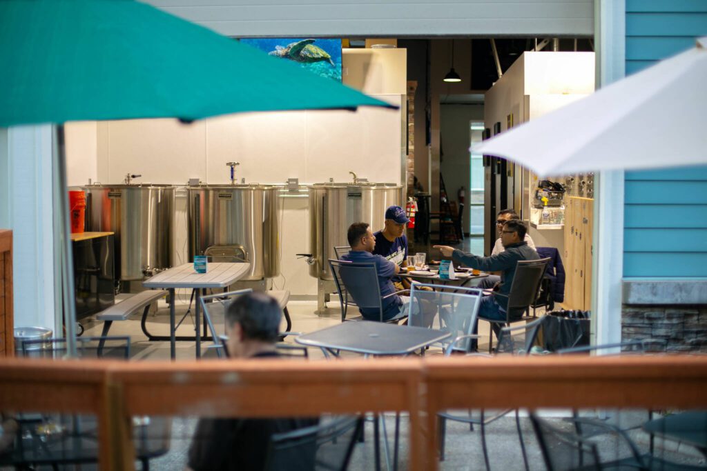 Patrons sit out on the patio and in the brewhouse at 4 Stitch Brewing Company on Friday, June 23, 2023, in Mill Creek, Washington. (Ryan Berry / The Herald)
