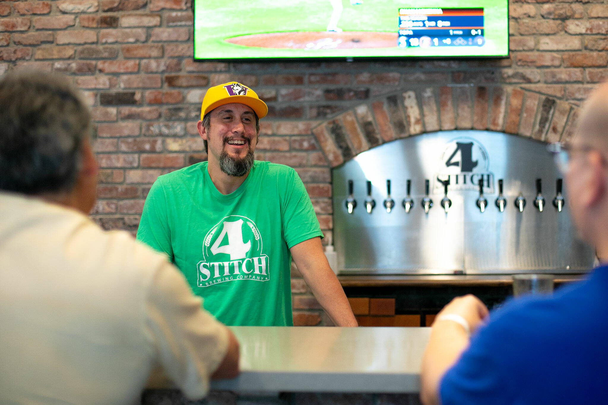 Matt Pereira, owner and brewer at 4 Stitch Brewing Company, talks with a couple of regulars at the bar on Friday, June 23, 2023, in Mill Creek, Washington. (Ryan Berry / The Herald)