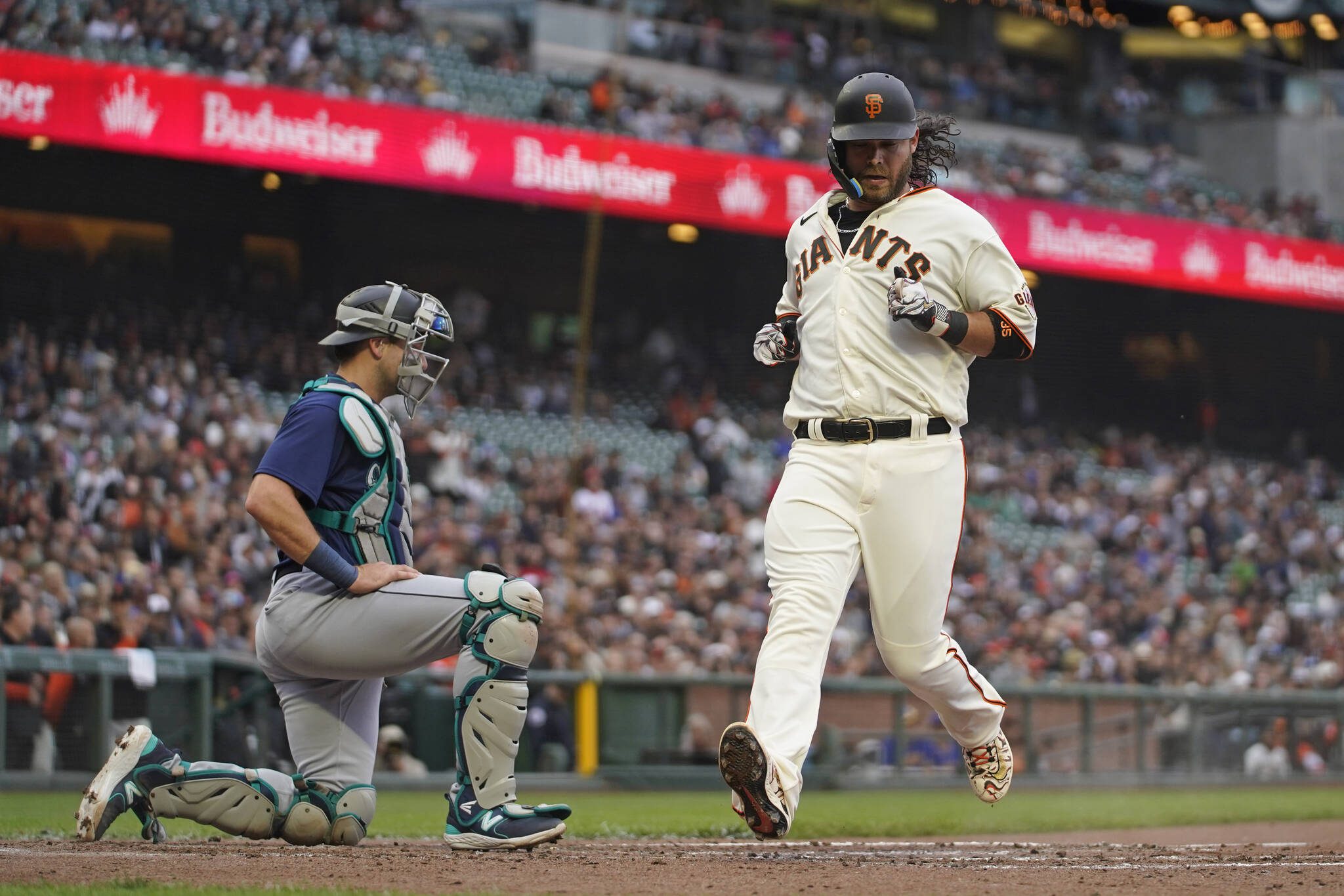 The Giants’ Brandon Crawford crosses home plate to score a run as Mariners catcher Cal Raleigh looks on in the third inning of a game on Wednesday in San Francisco. (AP Photo/Eric Risberg)