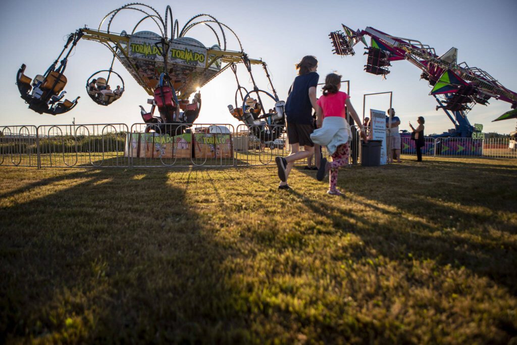 Kids run on the grass during the Kla Ha Ya Days carnival at Harvey Field in Snohomish, Washington on Thursday, July 13, 2023. (Annie Barker / The Herald)
