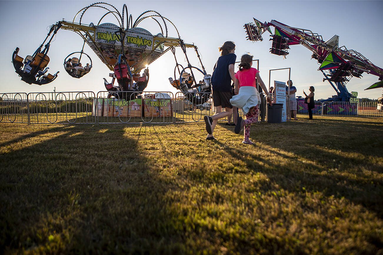 Kids run on the grass during the Kla Ha Ya Days carnival at Harvey Field in Snohomish, Washington on Thursday, July 13, 2023. (Annie Barker / The Herald)