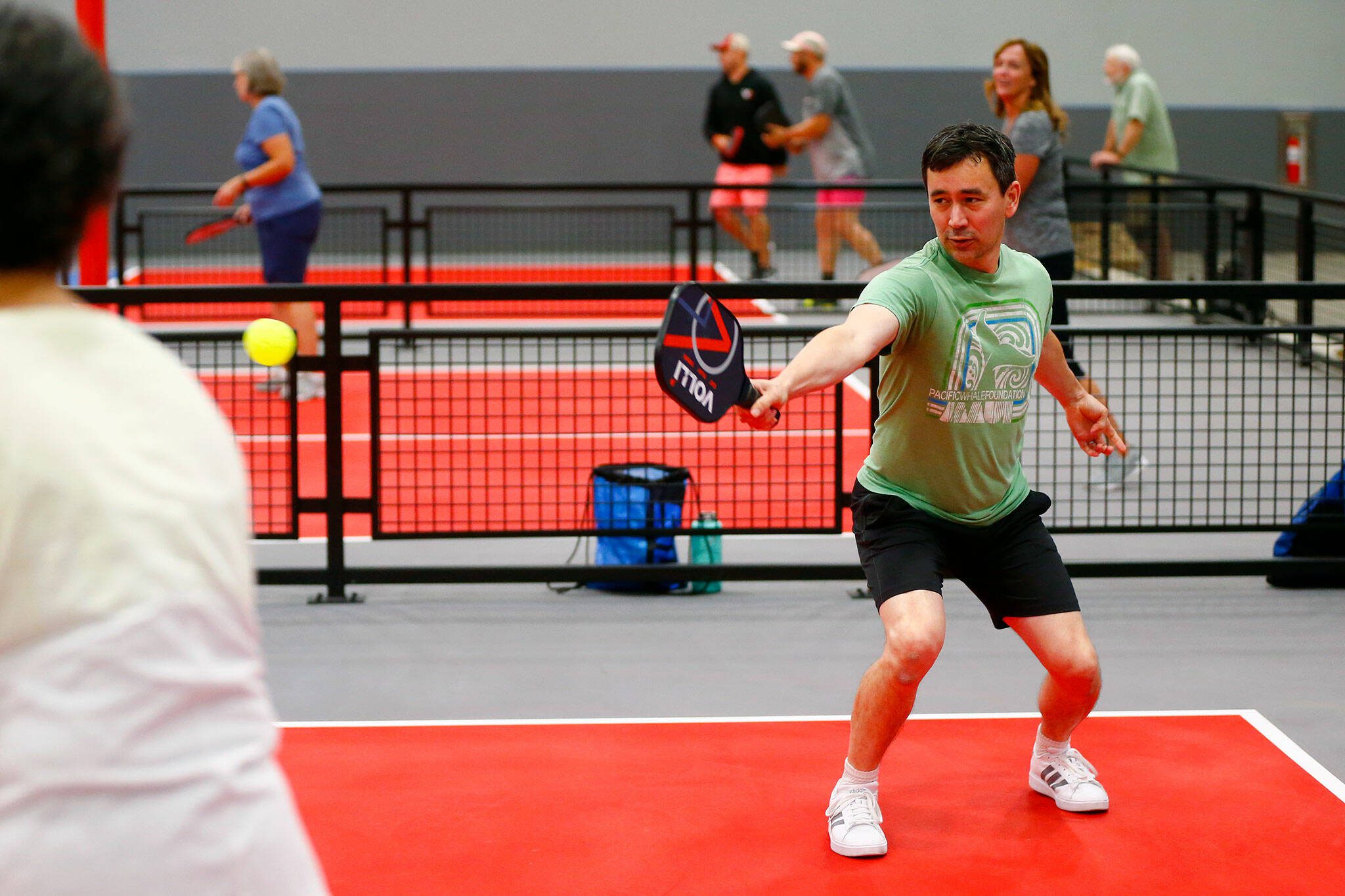 Herald sports reporter Nick Patterson returns the ball on the backhand while playing pickleball with his mother, Mary Jane Patterson, on Wednesday at VOLLI in Marysville. (Ryan Berry / The Herald)