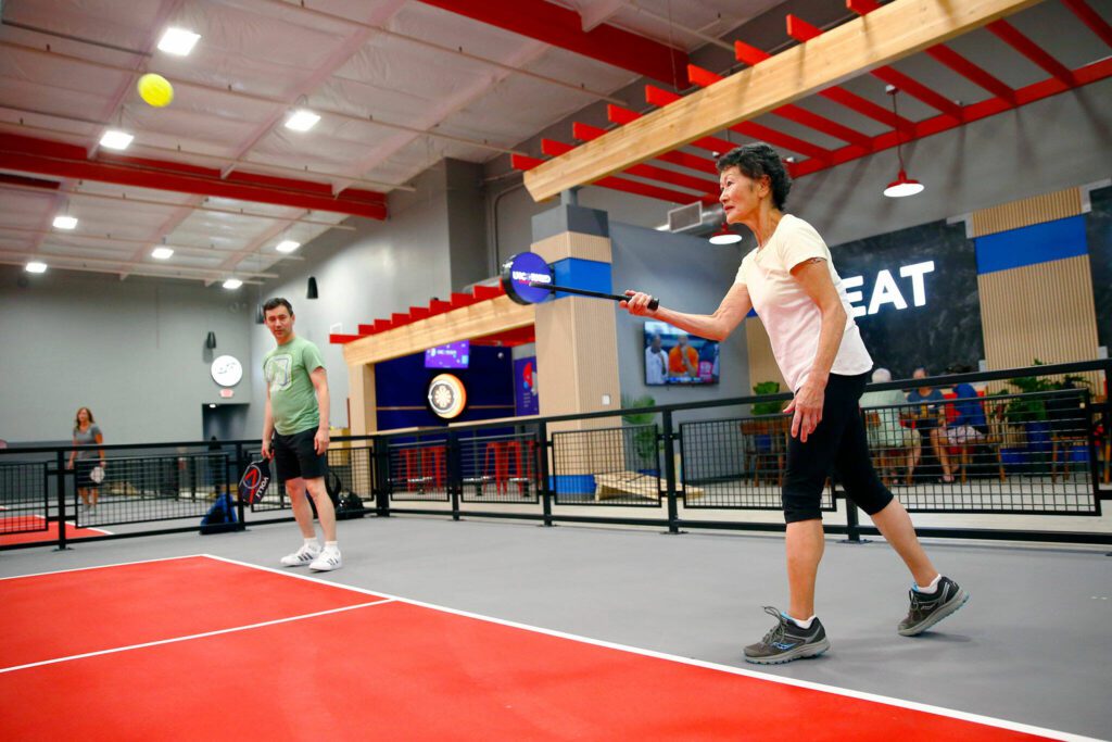 Mary Jane Patterson, mother of Herald sports reporter Nick Patterson, serves a ball while playing on a pickleball team with her son on Wednesday at VOLLI in Marysville. (Ryan Berry / The Herald)

