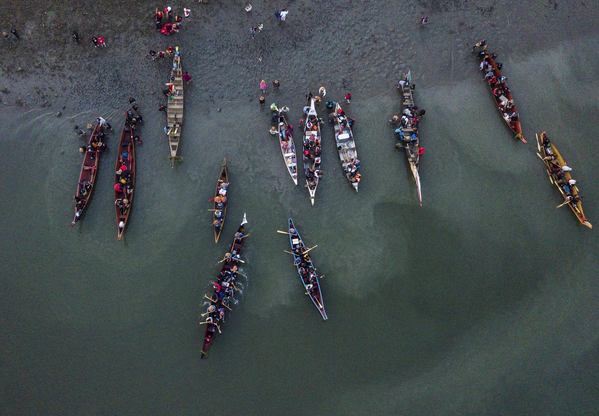 Dozens of colorful canoes are maneuvered into the water of Tulalip Bay as Canoe Families began another day of their journey to Muckleshoot on Friday, July 28, 2023 in Tulalip, Washington. (Olivia Vanni / The Herald)