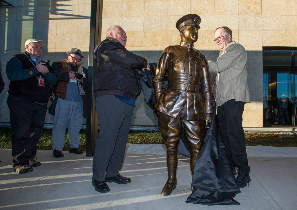 Two of Lt. Topliff Paine’s relatives, Nicholas Moe and Tom Paine reveal a life-size statue of the man on opening day of the Paine Field Terminal on Monday, March 4, 2019 in Everett, Wash. (Andy Bronson / The Herald)
