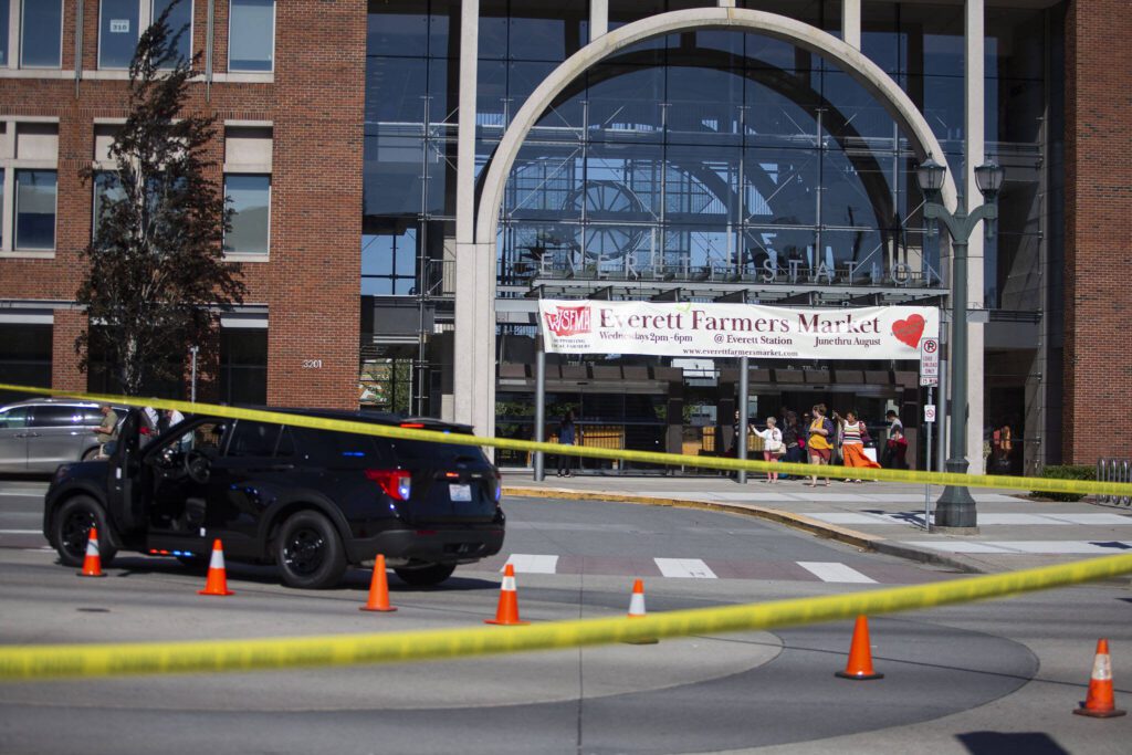 People walk out of Everett Station and point to the scene of a shooting on Smith Avenue on Tuesday, July 18, 2023 in Everett, Washington. (Olivia Vanni / The Herald)
