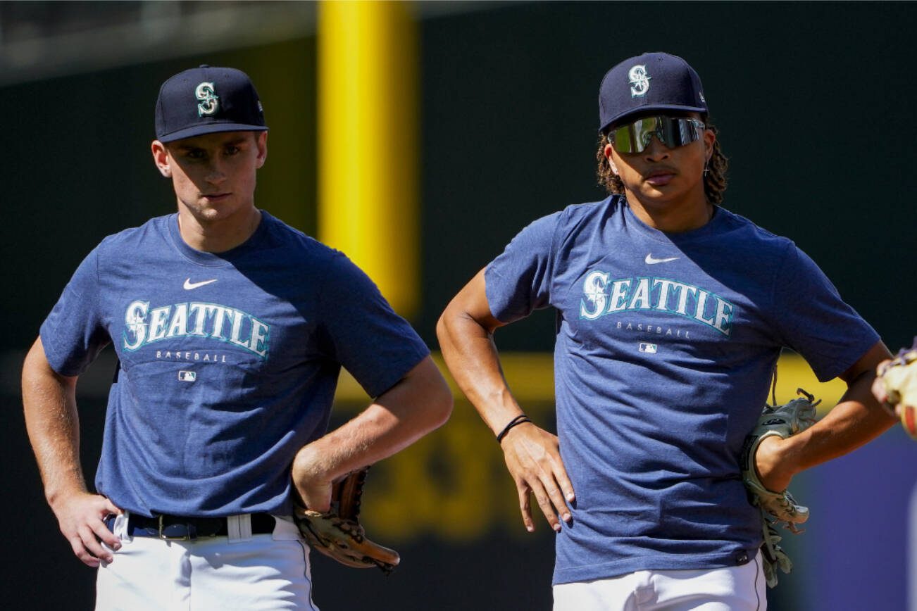 Seattle Mariners first-round draft picks Colt Emerson, left, and Tai Peete, center, participate in batting practice with shortstop J.P. Crawford, right, before the team's baseball game against the Minnesota Twins, Tuesday, July 18, 2023, in Seattle. (AP Photo/Lindsey Wasson)