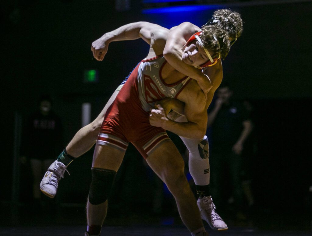 Arlington’s Dustin Baxter hangs on the back of Stanwood’s Ryder Bumgarner during the 170-pound match on Jan. 24 in Arlington. (Olivia Vanni / The Herald)
