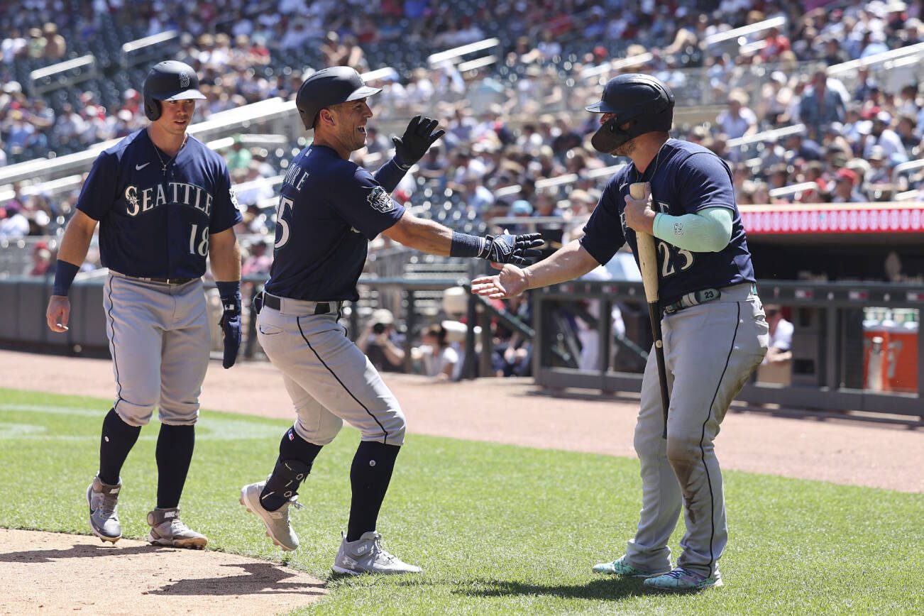 Seattle Mariners' Dylan Moore (25) celebrates with Ty France (23) after Moore hit a home run during the fifth inning of a baseball game against the Minnesota Twins, Wednesday, July 26, 2023, in Minneapolis. (AP Photo/Stacy Bengs)