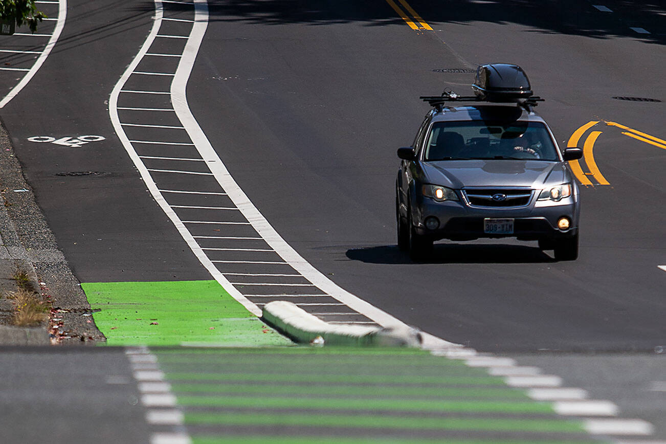 A car drives west on Madison Street past new bike lane curbs on Thursday, July 27, 2023 in Everett, Washington. (Olivia Vanni / The Herald)