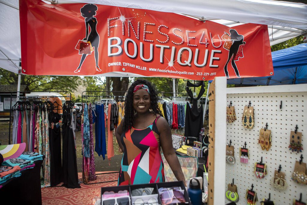 Finess4U Boutique Owner Tiffany Miller poses for a photo with her booth during the Nubian Jam at Forest Park in Everett, Washington on Saturday, July 29, 2023. (Annie Barker / The Herald)
