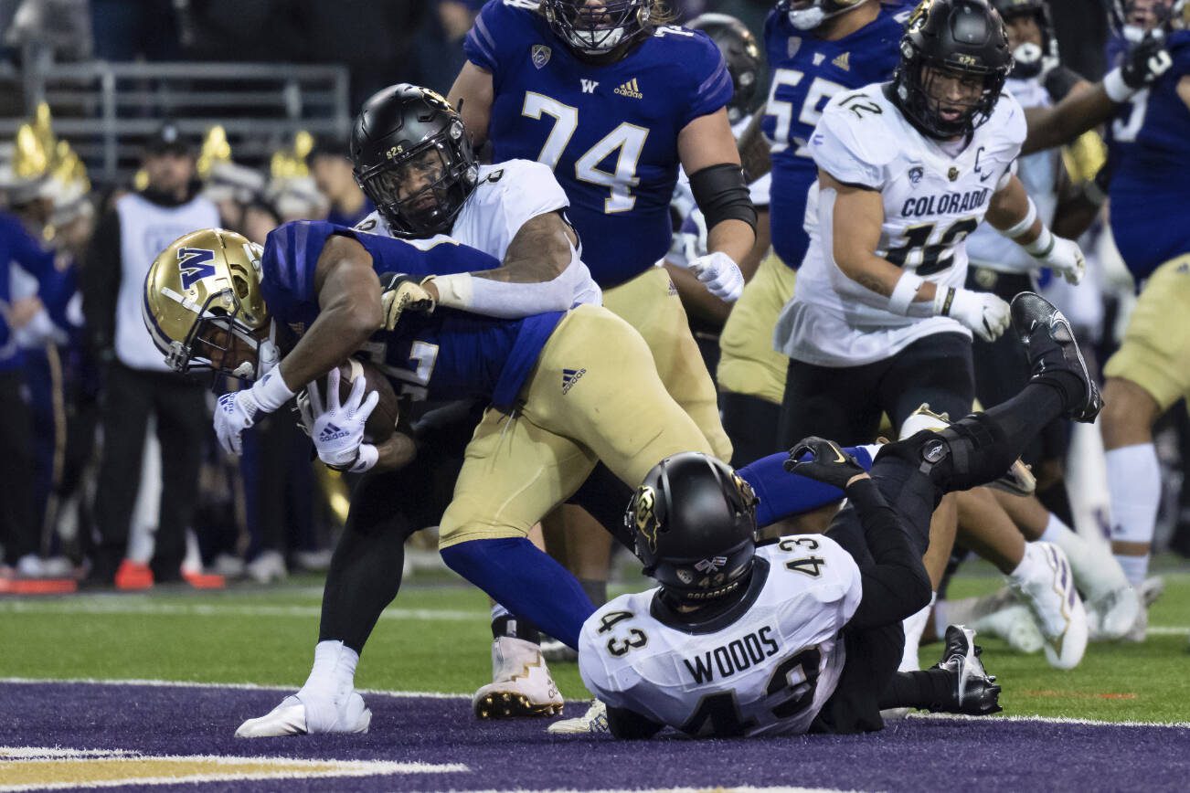 Washington running back Cameron Davis scores a touchdown against Colorado linebacker Josh Chandler-Semedo, second from left, and defensive back Trevor Woods during the first half of an NCAA college football game, Saturday, Nov. 19, 2022, in Seattle. (AP Photo/Stephen Brashear)