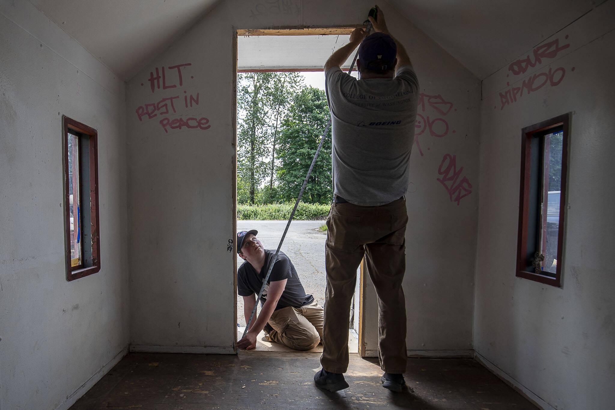 Michael Durkee, 15, left, holds a tape measure for Jeff Forbes, 60, right, at the Wayside Chapel along U.S. 2 in Monroe, Washington on Saturday, June 24, 2023. Michael Durkee, 15, is leading the effort for his Eagle Scout project. (Annie Barker / The Herald)