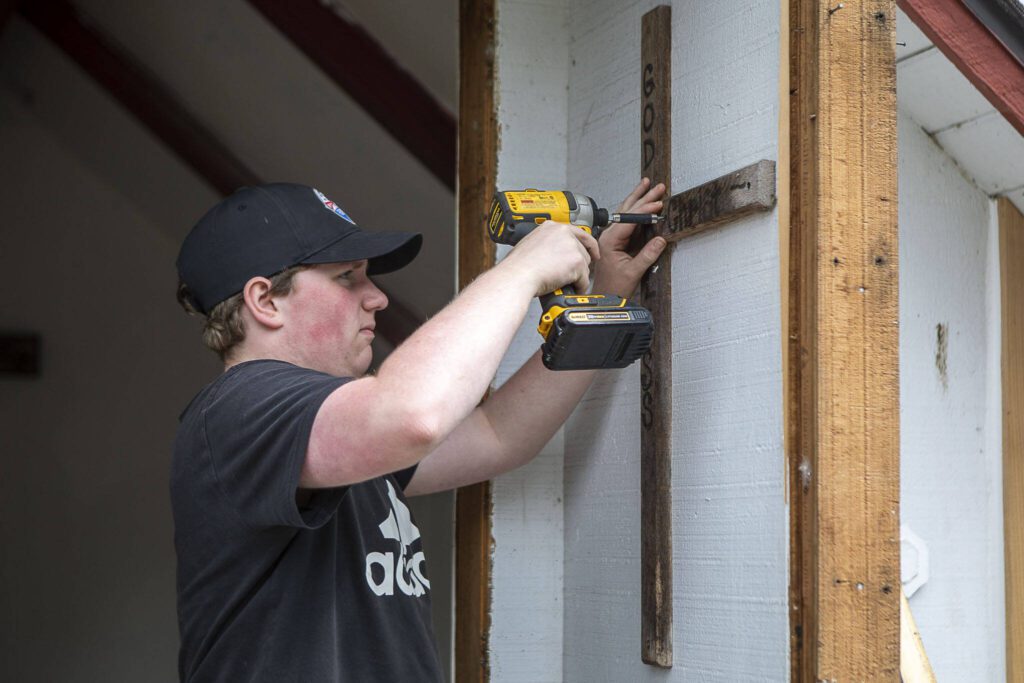 Michael Durkee, 15, unscrews hardware holding up a cross at the Wayside Chapel during a work session. Michael is leading the renovation effort for his Eagle Scout project. (Annie Barker / The Herald)
