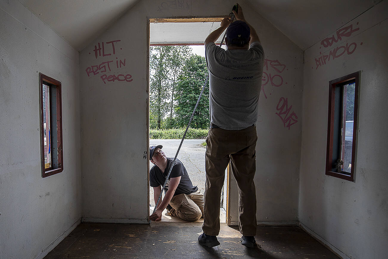 Michael Durkee, 15, left, holds a tape measure for Jeff Forbes, 60, right, at the Wayside Chapel along U.S. 2 in Monroe, Washington on Saturday, June 24, 2023. Michael Durkee, 15, is leading the effort for his Eagle Scout project. (Annie Barker / The Herald)