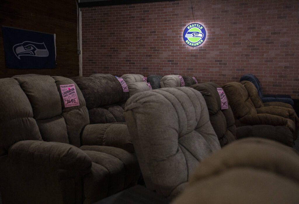 Furniture with liquidator price tags is illuminated by a Seahawks sign on Thursday, Aug. 24, 2023 in Everett, Washington. (Olivia Vanni / The Herald)
