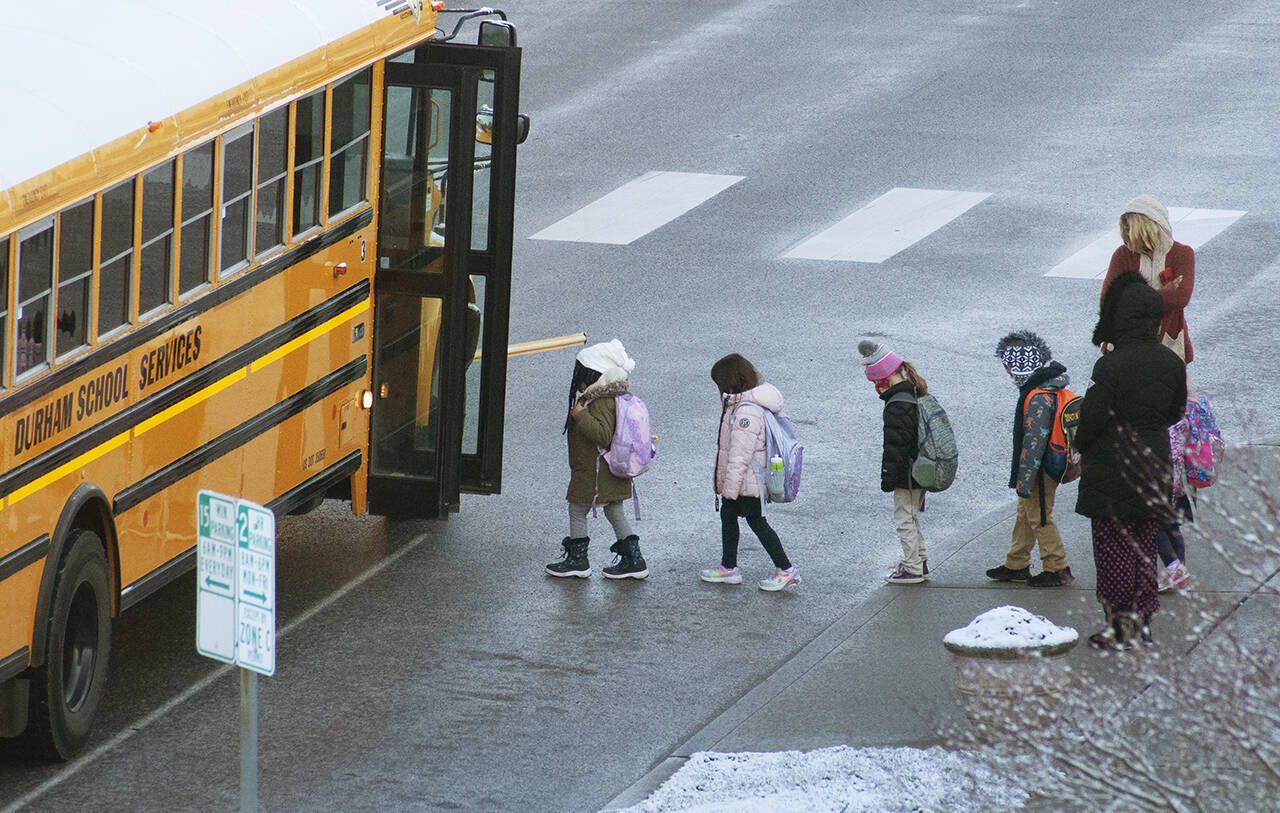 Children board a school bus on Feb. 24, 2022, in Everett, Washington. (Sue Misao / The Herald)