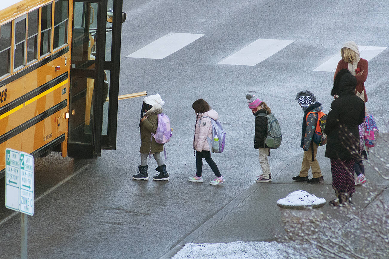 Children board a school bus in Everett on Thursday morning. (Sue Misao / The Herald) Feb. 24, 2022