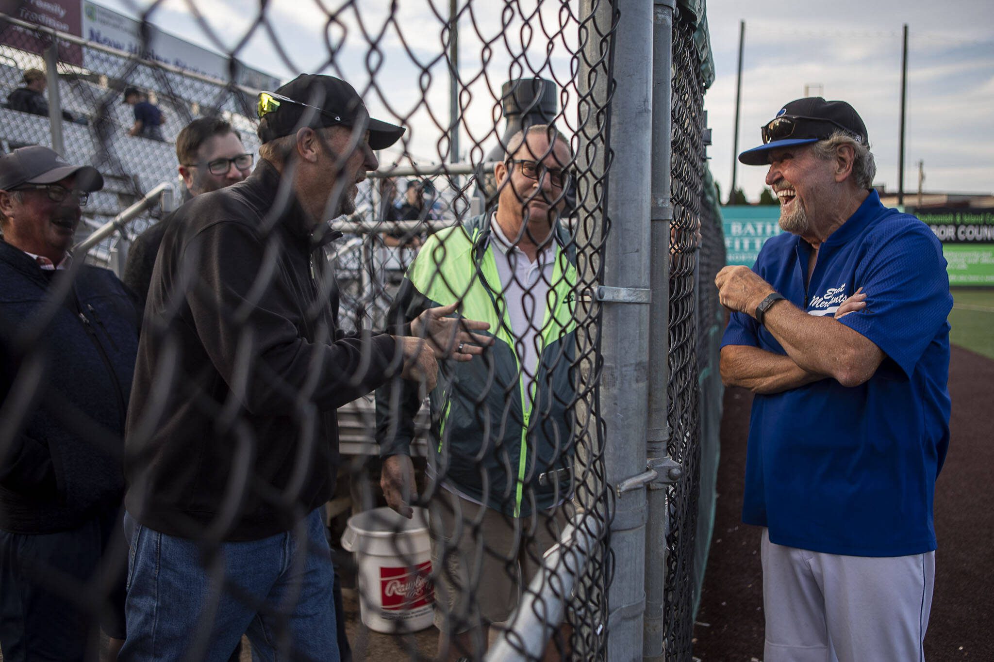 Everett Merchants manager and Snohomish County Sports Hall of Famer Harold Pyatte (right) laughs with former players during a game on Friday at Funko Field in Everett. This was Pyatte’s final game after 50 years as the Merchants coach. (Annie Barker / The Herald)