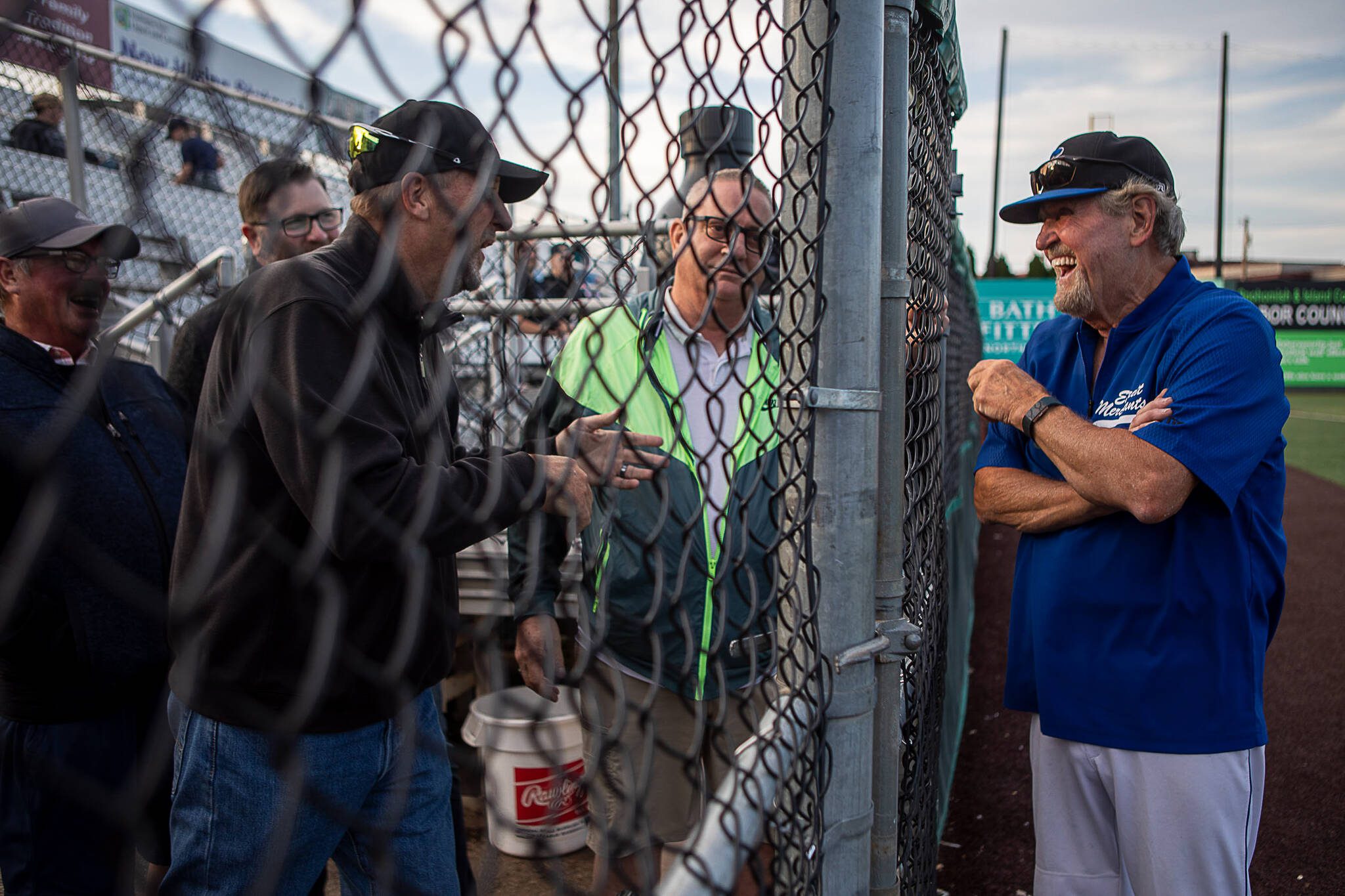 Everett Merchants manager and Snohomish County Sports Hall of Famer Harold Pyatte, right, laughs with former players during a game at Funk Field in Everett, Washington on Friday, July 28, 2023. This was Pyatte’s final game after 50 years as a baseball coach. (Annie Barker / The Herald)