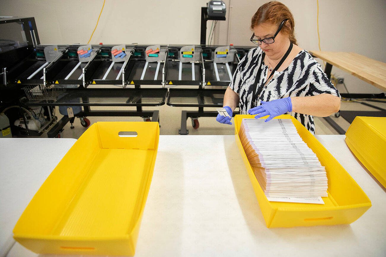 Elections assistant Kathleen Strong collects sorted ballots on Tuesday, Aug. 1, 2023 in Everett, Washington. (Olivia Vanni / The Herald)