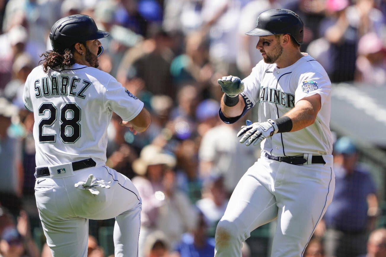 Seattle Mariners' Eugenio Suarez (28) greets Cal Raleigh after scoring on Raleigh's two-run home run against the Boston Red Sox during the sixth inning of a baseball game Wednesday, Aug. 2, 2023, in Seattle. (AP Photo/Lindsey Wasson)