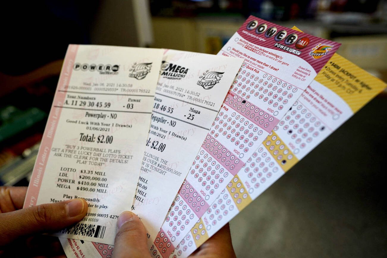 A customer shows her purchased Powerball and Mega Millions tickets at a convenience store in Northbrook, Ill., Wednesday, Jan. 6, 2021. The Powerball jackpot is up to $410 million. The drawing for that is Wednesday night. The Mega Millions jackpot for Friday's lottery drawing has jumped to $490 million and it potentially makes the 8th largest in the game's history. At $857 million, this is the highest combined jackpot total for the multi-state jackpot games in more than two years. Mega Millions is played in 45 states, as well as Washington, D.C., and the U.S. Virgin Islands. (AP Photo/Nam Y. Huh)