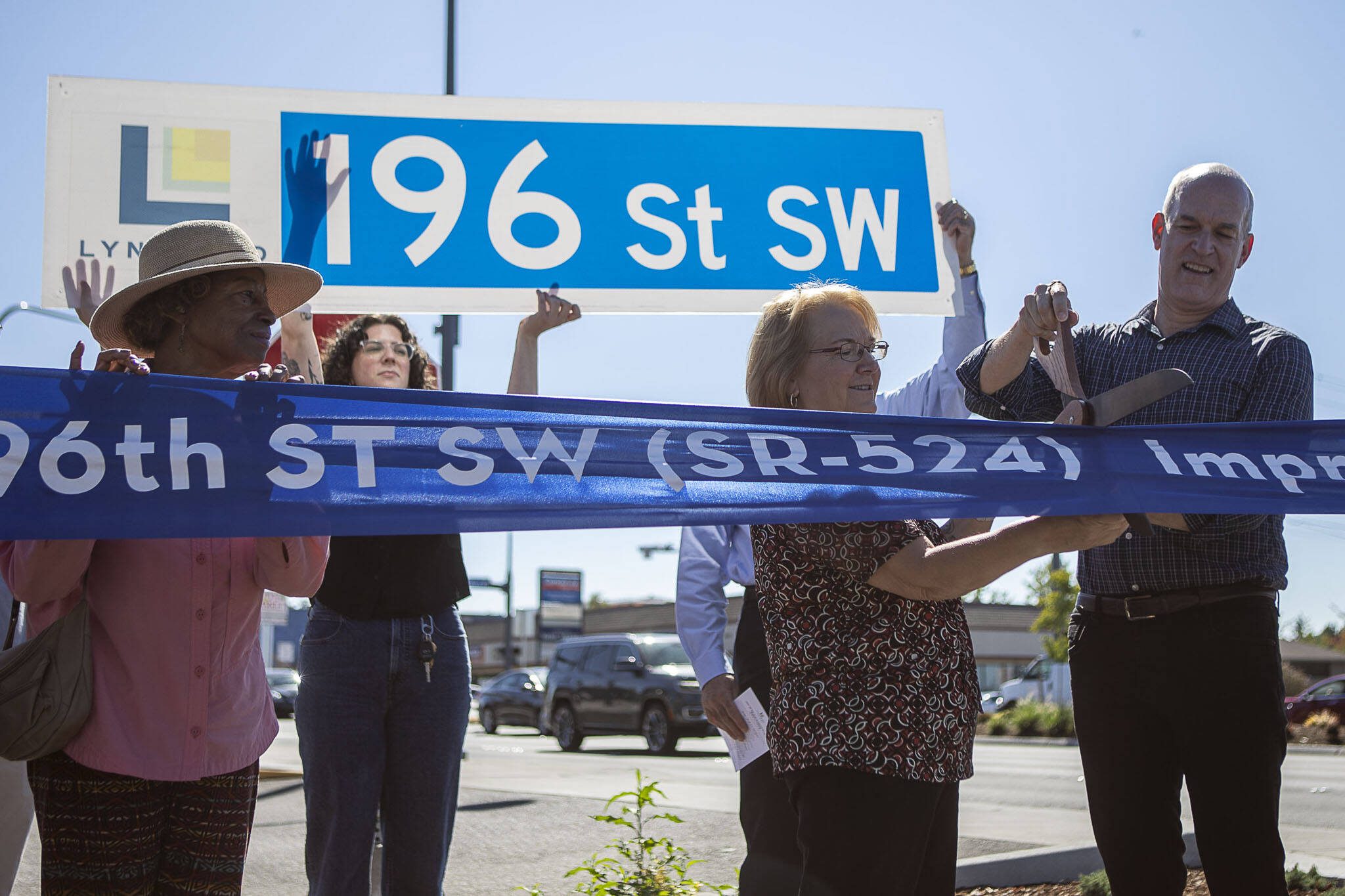 Lynnwood Mayor Christine Frizzell, second from right, and Rep. Rick Larsen, right, cut a ribbon during a ceremony to celebrate the completion of the 196th Street SW Improvement Project near the 196th and 44th Ave West intersection in Lynnwood, Washington on Tuesday, Aug. 15, 2023. (Annie Barker / The Herald)