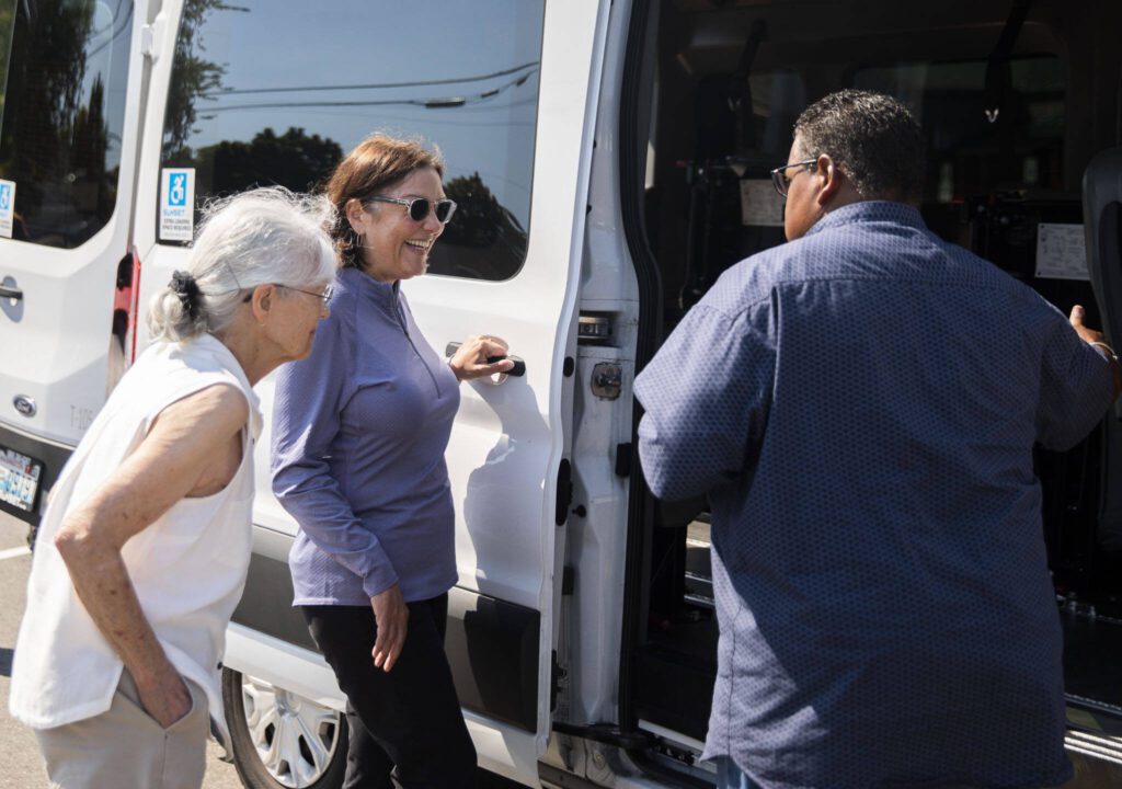 Char McCain, left, U.S. Congresswoman Suzan DelBene, center, and Lloyd White, talk about one of the current Homage transportation vehicles on Monday, Aug. 14, 2023 in Lynnwood, Washington. (Olivia Vanni / The Herald)
