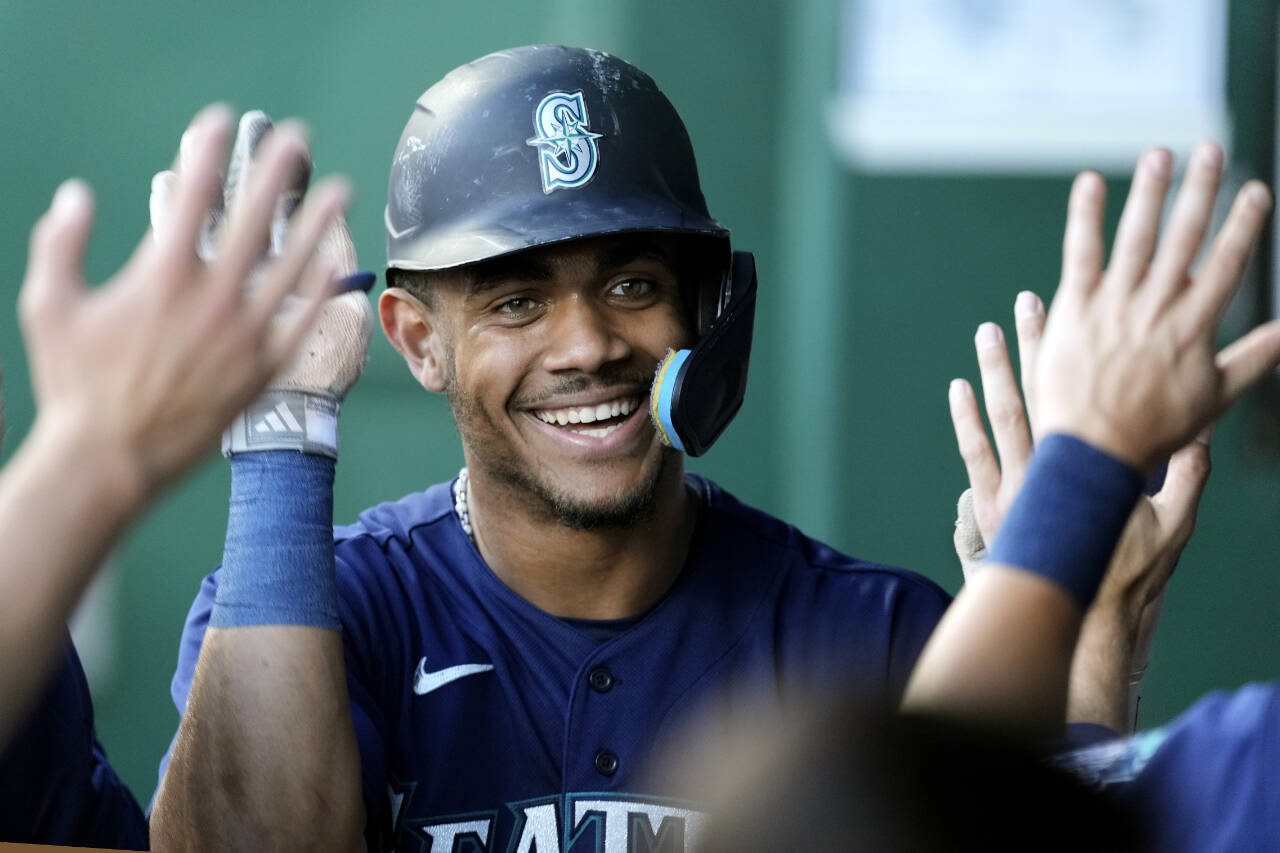 Seattle Mariners’ Julio Rodriguez celebrates in the dugout after scoring on a single by Ty France during the first inning of Wednesday’s game against the Kansas City Royals in Kansas City, Mo. (AP Photo/Charlie Riedel)