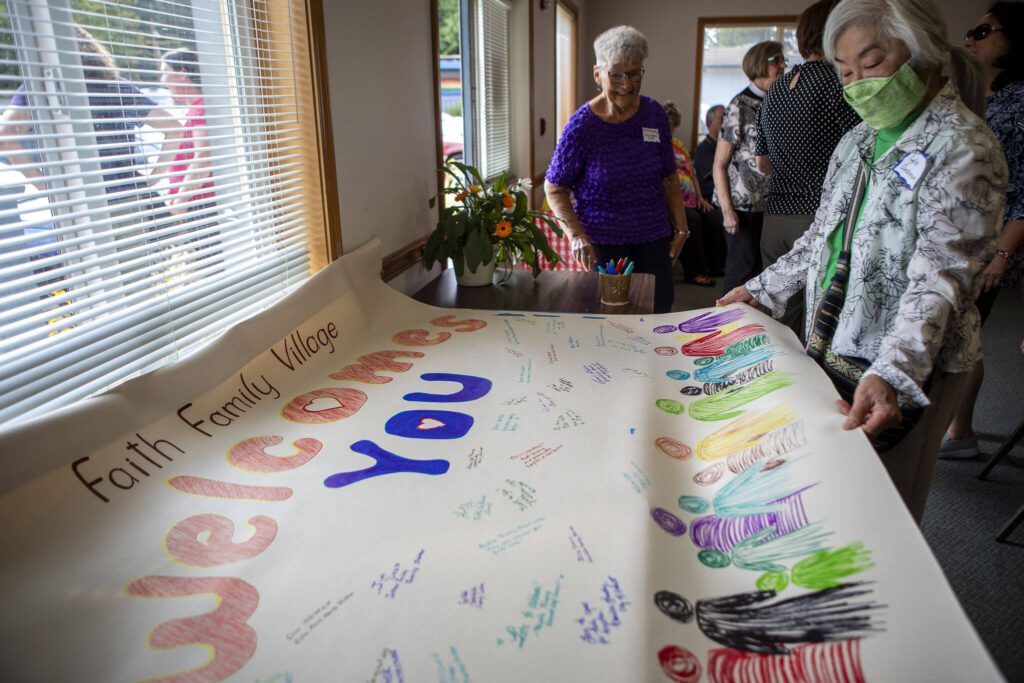 Lyla Anderson holds up a welcome sign for future families during a groundbreaking ceremony for Faith Family Village at Faith Lutheran Church in Everett, Washington on Monday, Aug. 21, 2023. (Annie Barker / The Herald)
