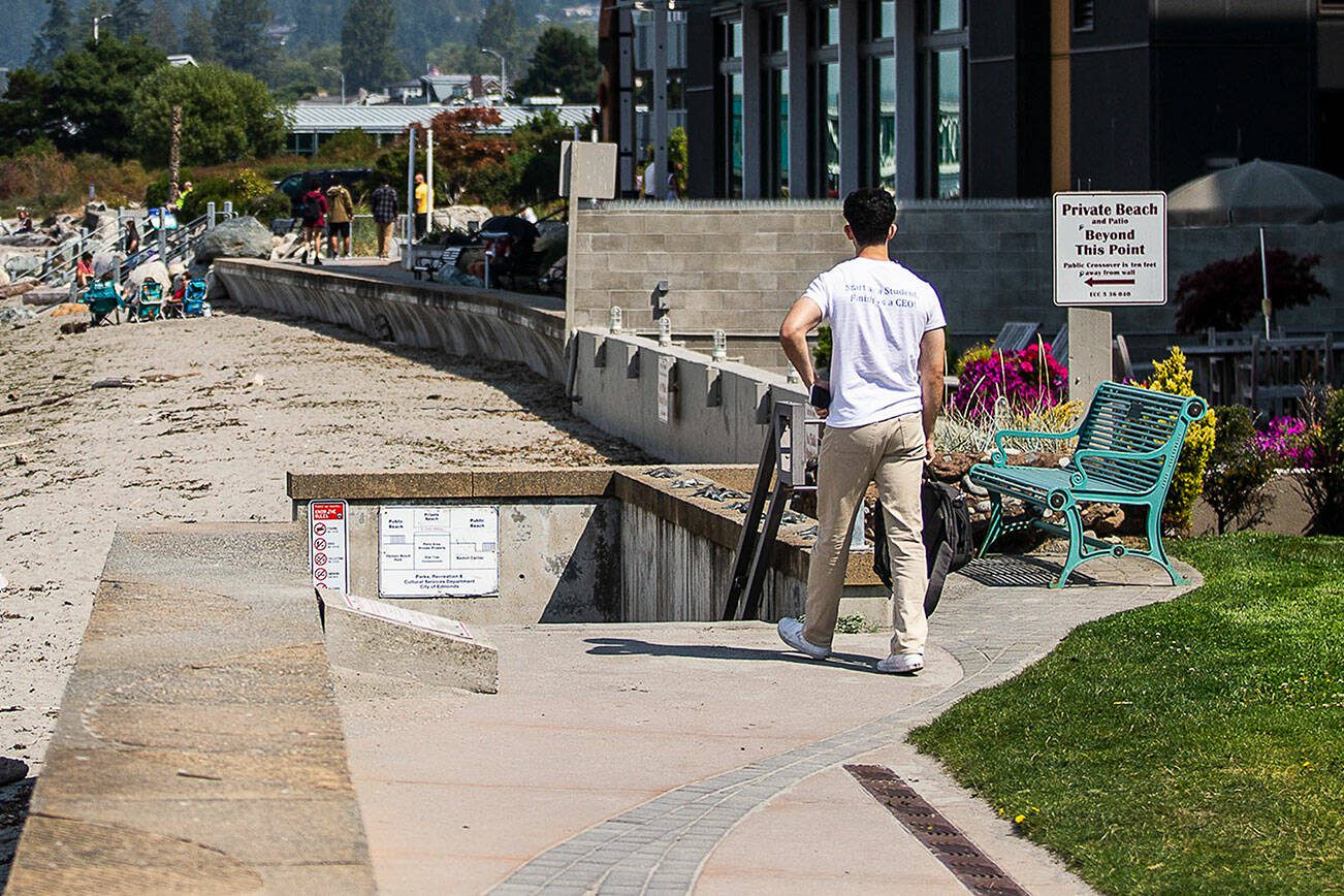 A man pauses to read a sign alerting beach users to the private section of the beach along the Edmonds waterfront on Friday, Aug. 25, 2023 in Edmonds, Washington. (Olivia Vanni / The Herald)
