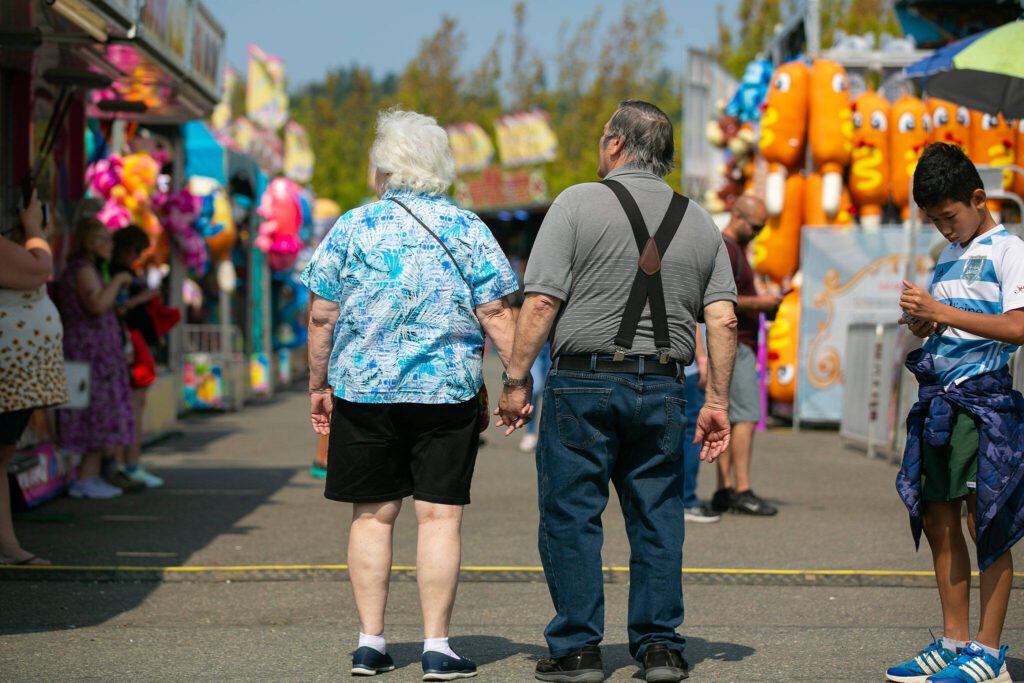 A couple stops to look around as they stroll through the carnival during opening day of the Evergreen State Fair on Thursday, August 24, 2023, in Monroe, Washington. (Ryan Berry / The Herald)
