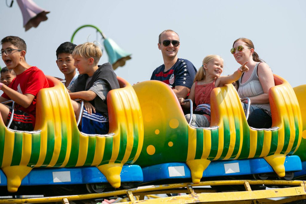 Children and parents ride the kids roller coaster during opening day of the Evergreen State Fair on Thursday, August 24, 2023, in Monroe, Washington. (Ryan Berry / The Herald)
