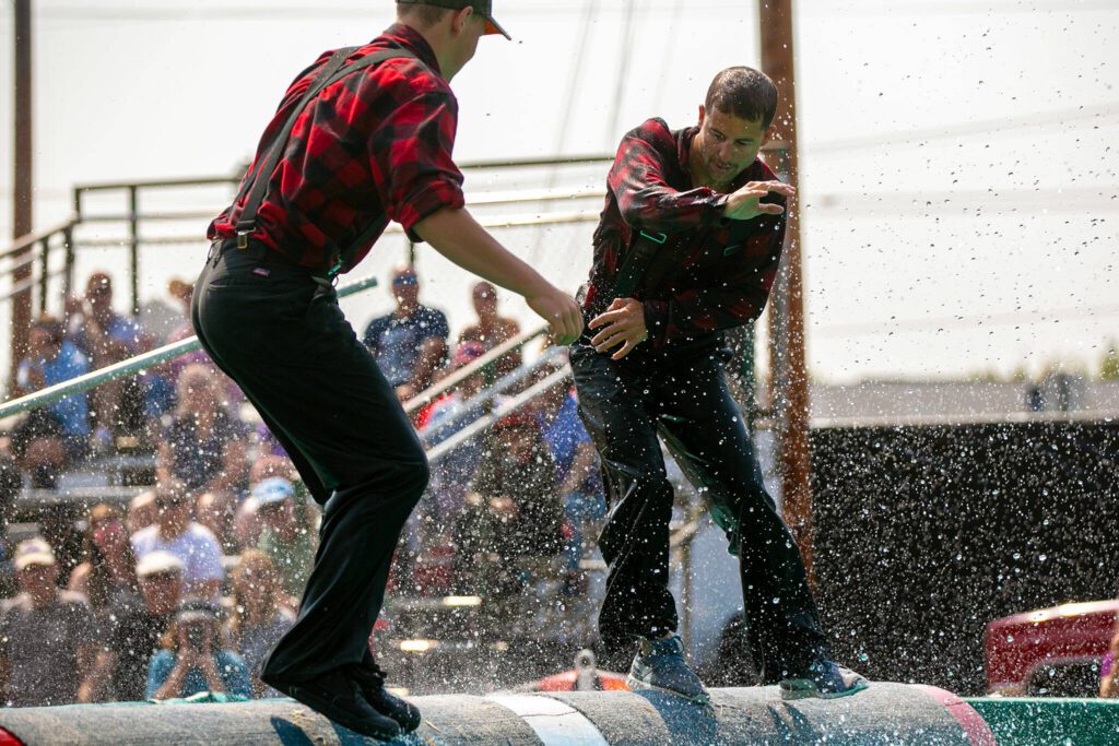 Two lumberjacks compete against each other in log rolling during the International Lumberjack Show on opening day of the Evergreen State Fair on Thursday, August 24, 2023, in Monroe, Washington. (Ryan Berry / The Herald)
