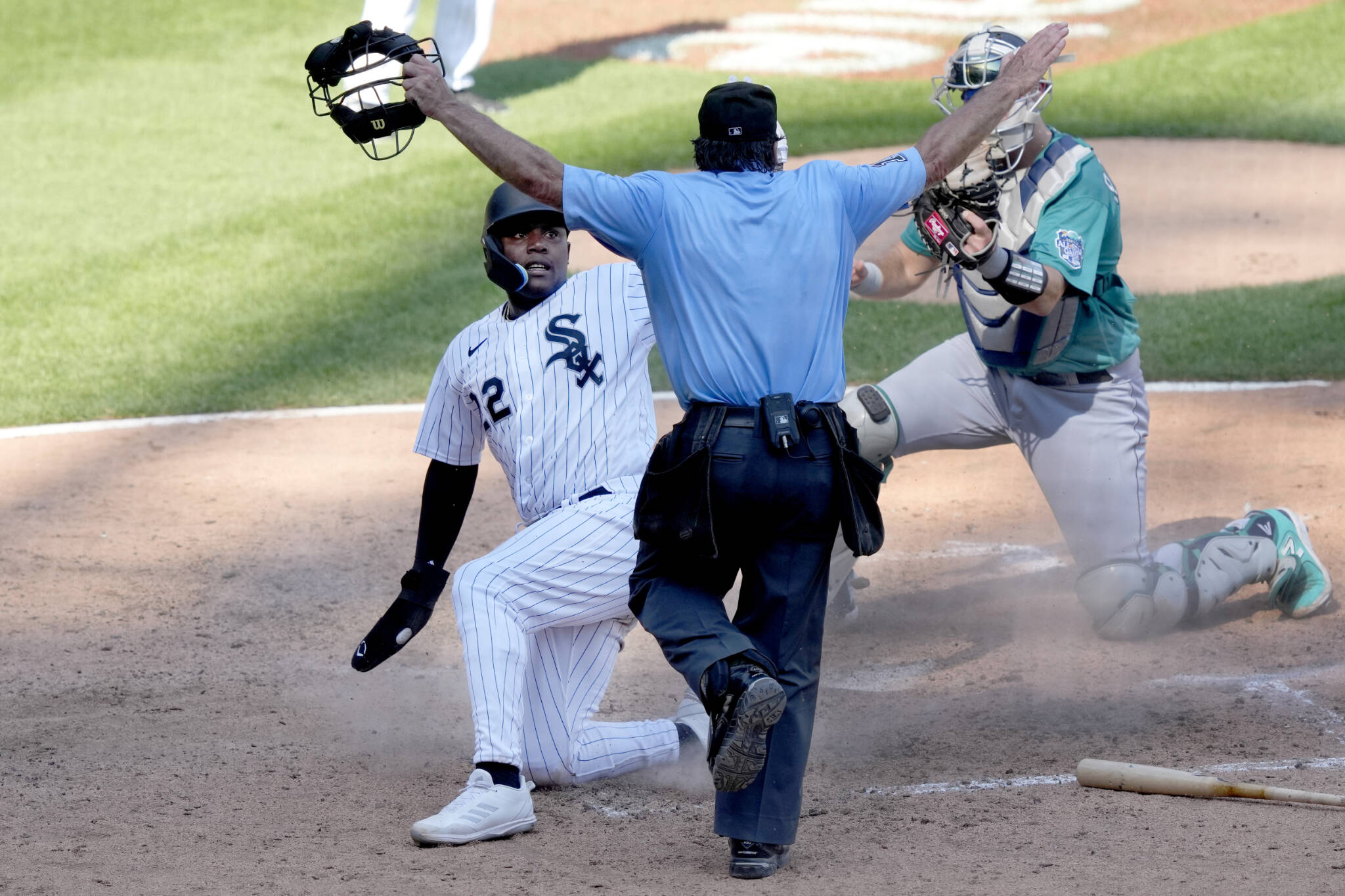 Home plate umpire Phil Cuzzi calls the White Sox’s Oscar Colas safe at home as Mariners catcher Cal Raleigh shows Cuzzi the ball during the ninth inning of a game Wednesday in Chicago. (AP Photo/Charles Rex Arbogast)