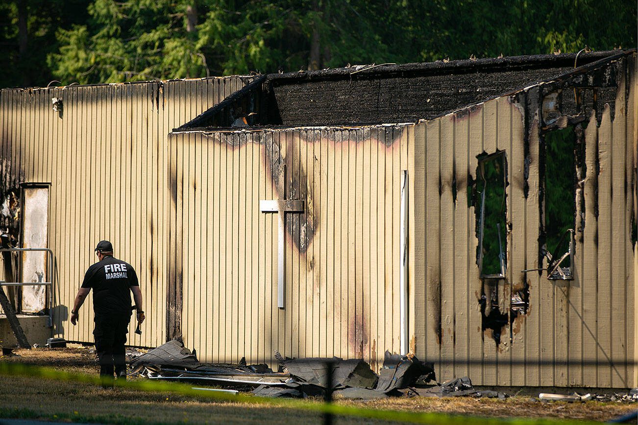 A member of the Fire Marshal’s Office circles the remnants of Seattle Laestadian Lutheran Church after it was completely destroyed by a fire Friday, August 25, 2023, near Maltby, Washington. (Ryan Berry / The Herald)