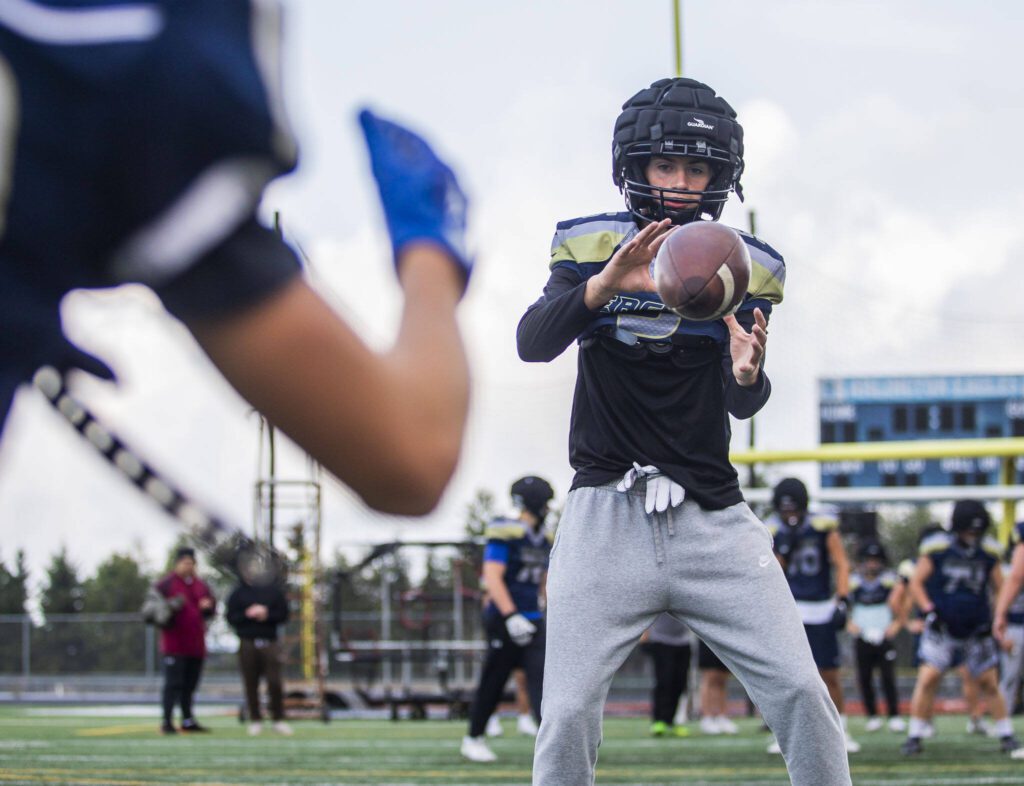 Jacoby Favor catches a snap during practice on Wednesday at Arlington High School. (Olivia Vanni / The Herald)
